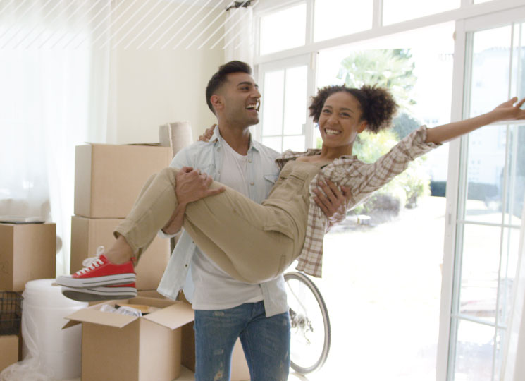 Happy couple celebrating in their new home surrounded by moving boxes.
