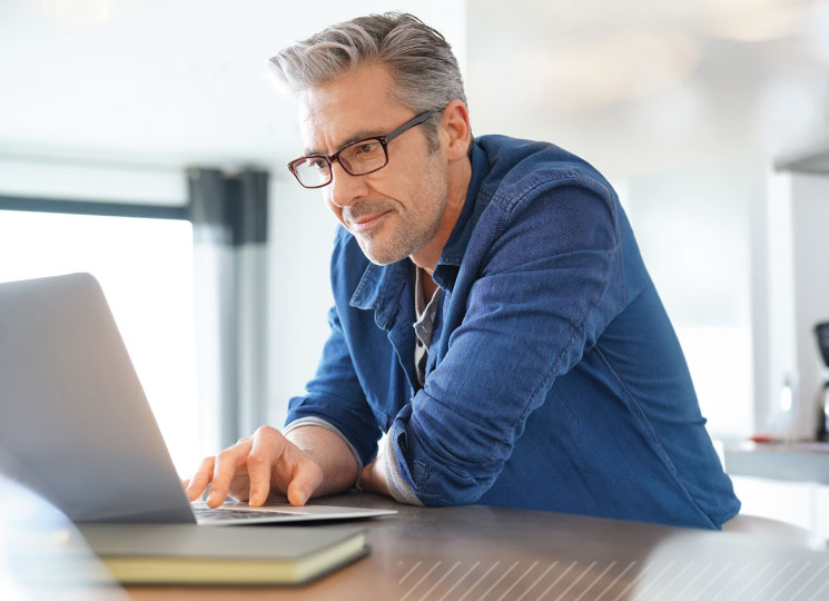 Man reviewing CD Rates on a laptop at home.