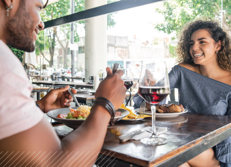 Couple enjoying a meal and conversation at an outdoor restaurant.