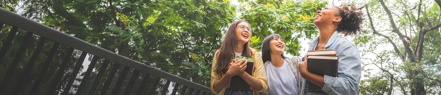 Student Checking Account in Iowa for friends laughing on campus with books.