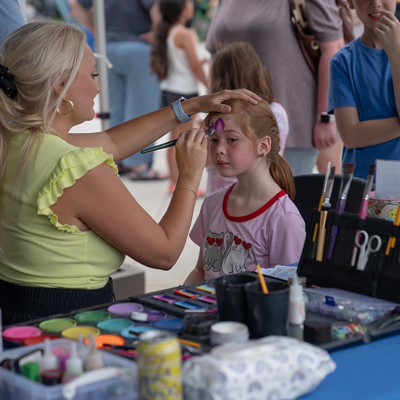 A child gets her face painted at Marion by Moonlight during the first night of the 2026 concert series.
