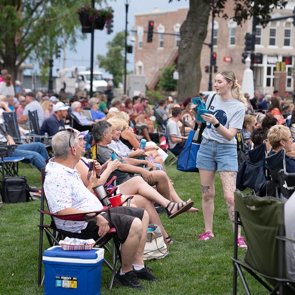 A volunteer hands out items to guests seated in lawn chairs at Marion by Moonlight in Central Plaza.