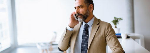 Man in a suit taking a serious phone call in a bright office.
