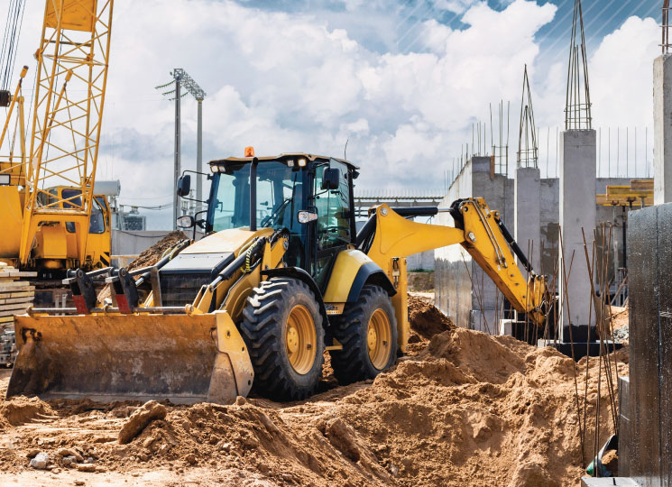 Construction equipment including a backhoe and crane at an active job site.