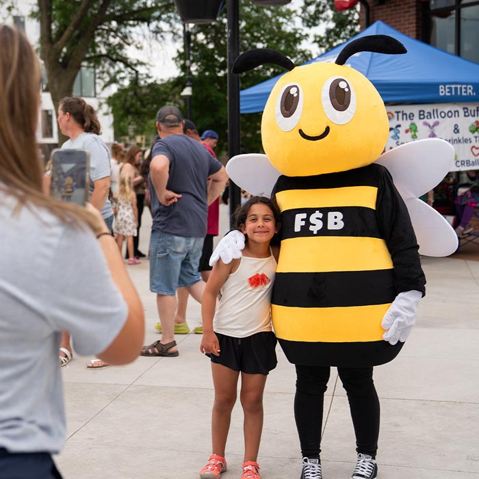 A child poses with FSB’s bee mascot, Cash, during Marion by Moonlight in downtown Marion.
