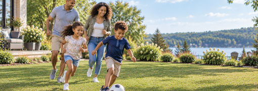 Family playing soccer together in their backyard on a sunny day near a lake.