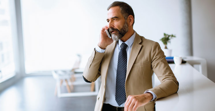 Man in a suit taking a serious phone call in a bright office.