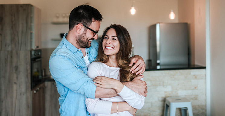 Happy couple embracing in their new home after buying their first house.